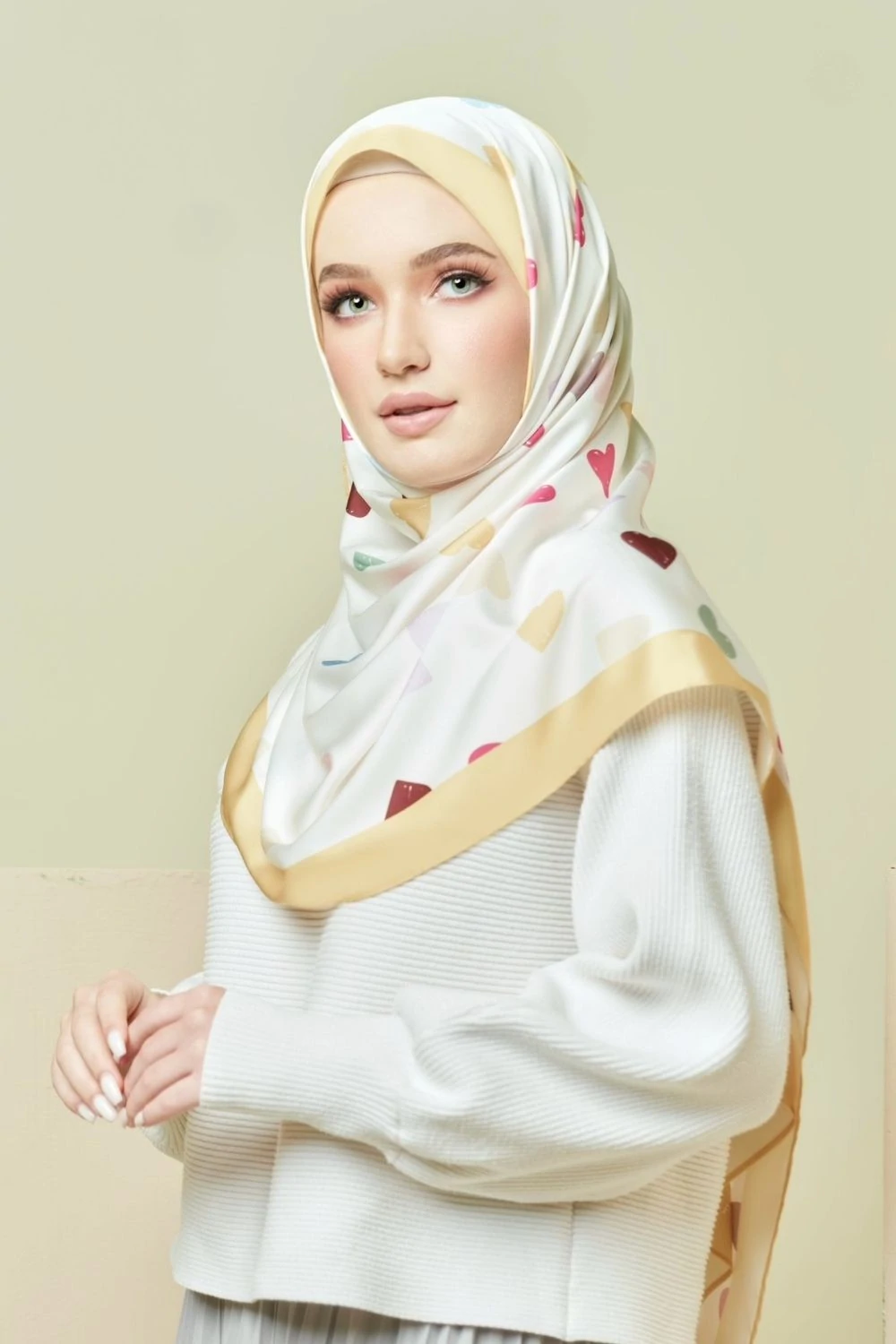 Woman wearing a white hijab with colorful patterns on a beige background