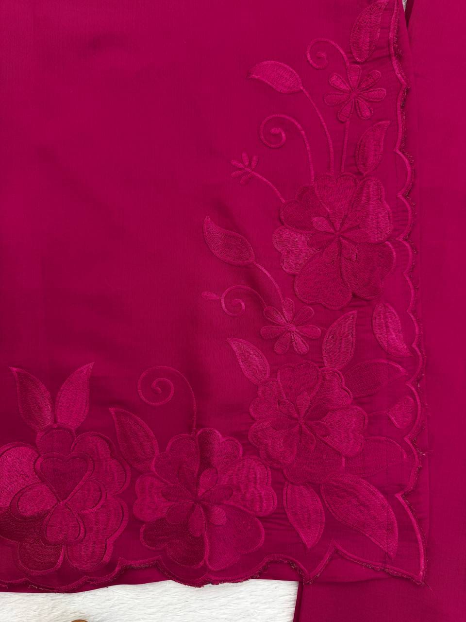 Close-up of a pink fabric with floral embroidery on a white background