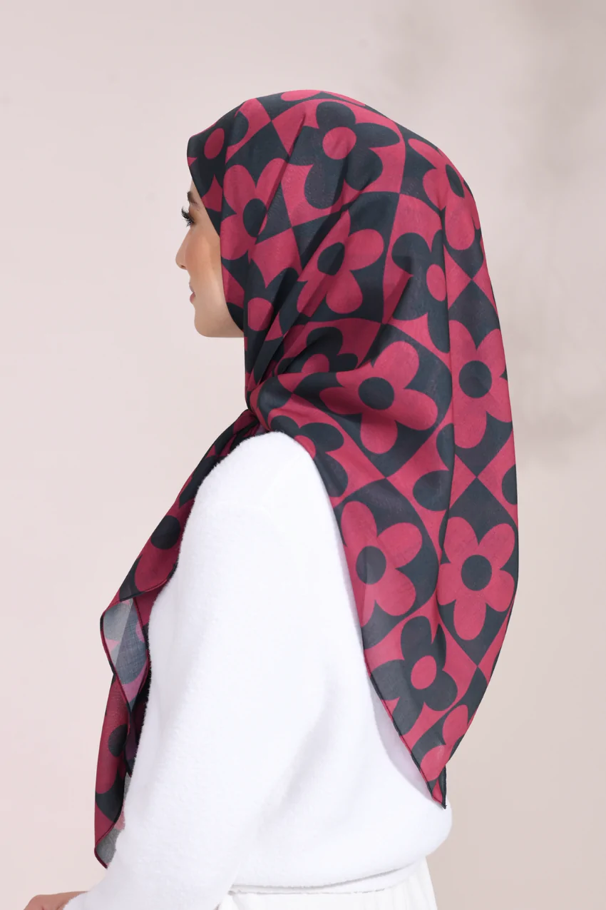 Person wearing a red and black floral patterned hijab on a plain background