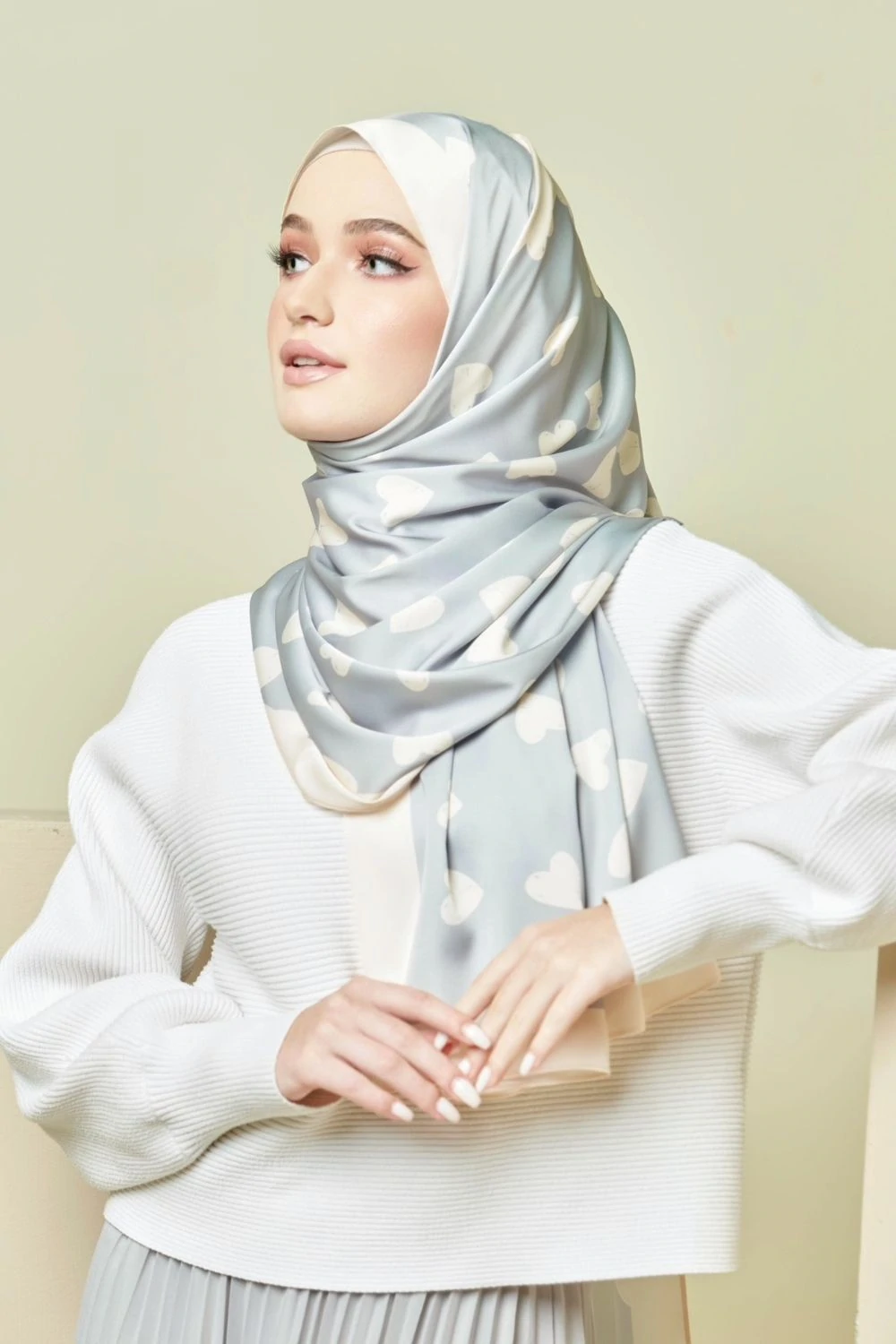 Woman wearing a light gray hijab with subtle patterns against a plain background